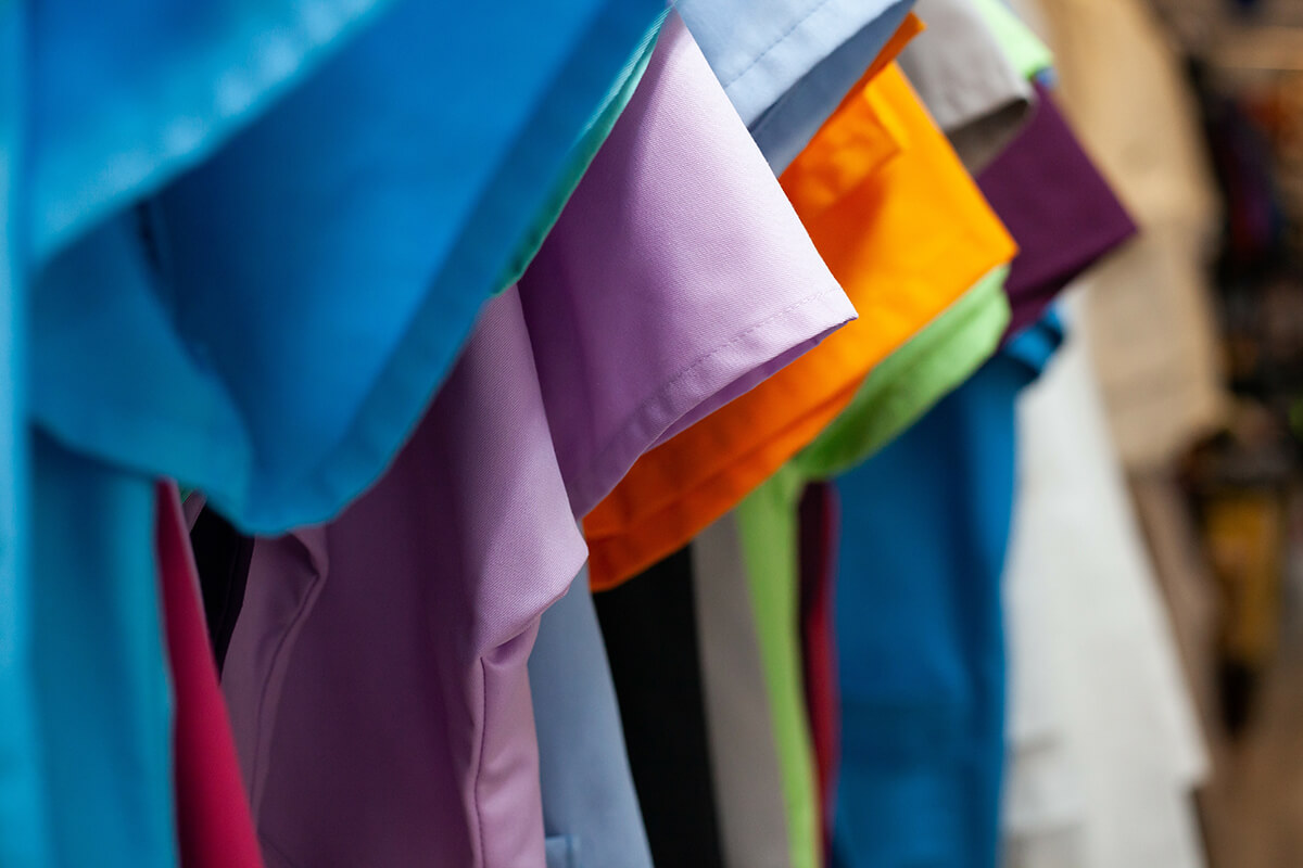 details of clothing and textile on display in clothing store folded, stacked and hanging